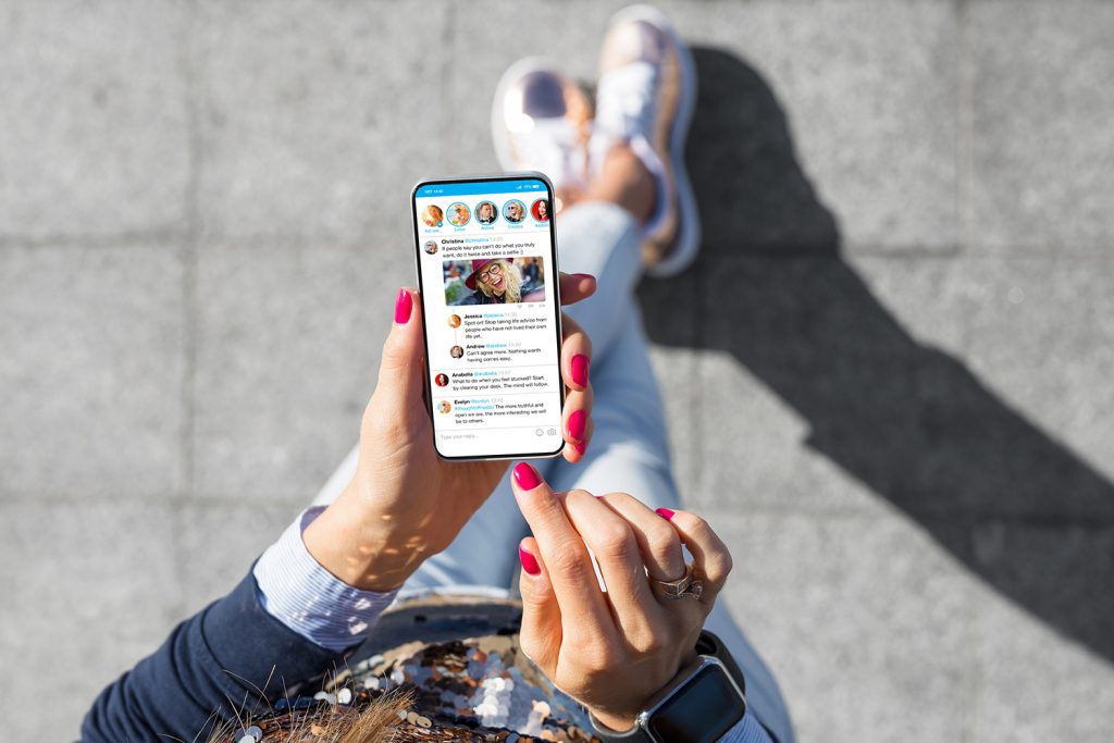 An overhead view of a woman looking at her cell phone to post on social media.