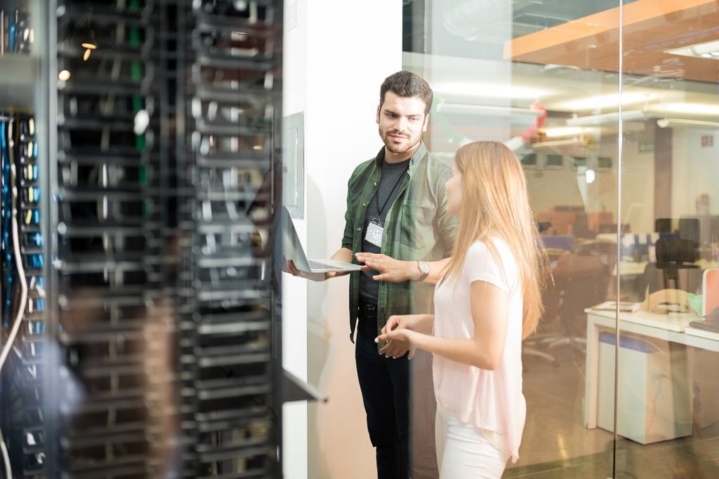 A man and women pair of colleagues who are discussing work in a server room
