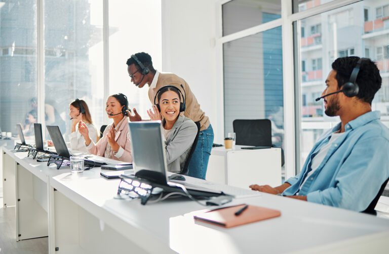 A group of employees on computers with headsets.